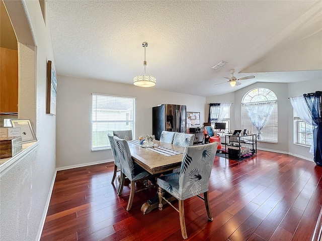 dining space featuring ceiling fan, dark hardwood / wood-style flooring, vaulted ceiling, and a textured ceiling