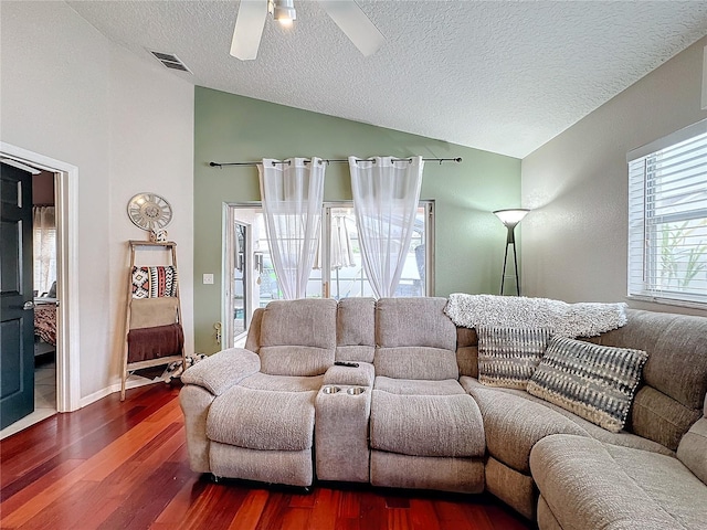 living room with vaulted ceiling, a wealth of natural light, a textured ceiling, and dark hardwood / wood-style flooring