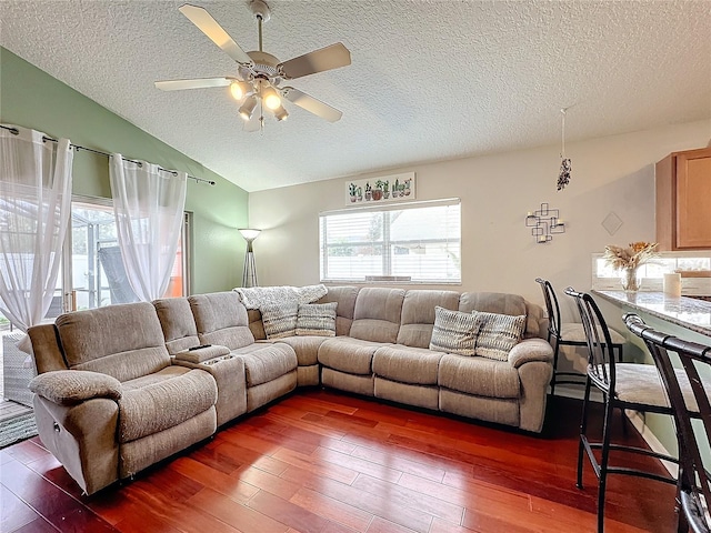 living room featuring a textured ceiling, vaulted ceiling, dark hardwood / wood-style floors, and ceiling fan