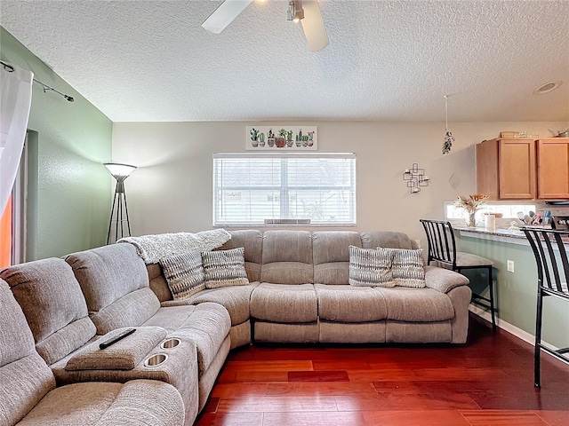 living room with ceiling fan, dark hardwood / wood-style floors, and a textured ceiling