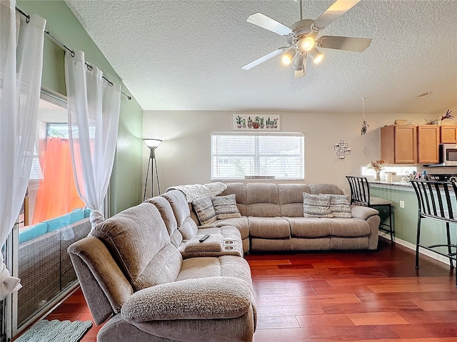 living room with ceiling fan, dark hardwood / wood-style floors, and a textured ceiling