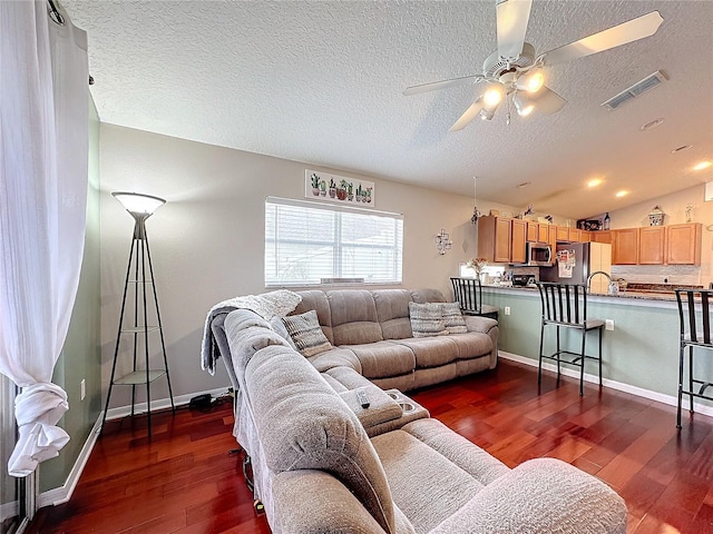 living room featuring ceiling fan, dark hardwood / wood-style floors, vaulted ceiling, and a textured ceiling