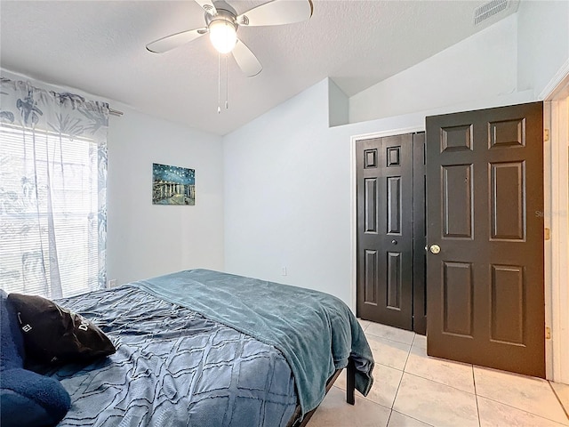 tiled bedroom featuring vaulted ceiling, ceiling fan, and a closet