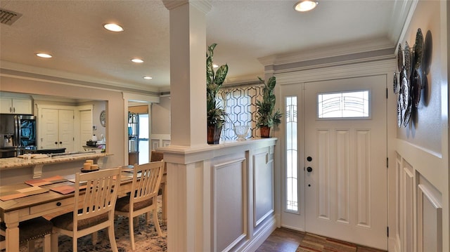 entryway featuring hardwood / wood-style flooring, crown molding, and decorative columns