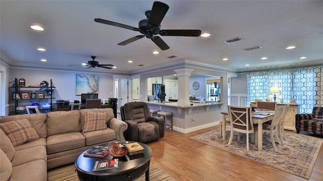 living room with decorative columns, ornamental molding, ceiling fan, and light hardwood / wood-style flooring