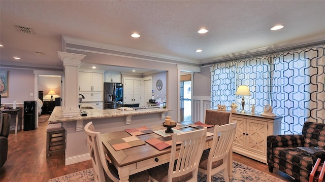 dining area featuring crown molding, dark hardwood / wood-style floors, and decorative columns