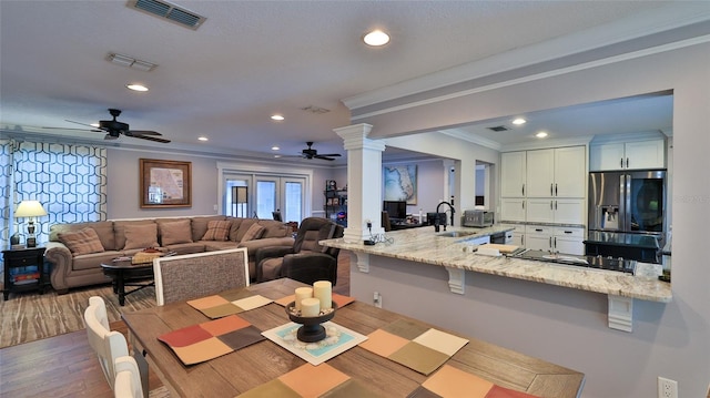 dining room with sink, ornate columns, crown molding, ceiling fan, and hardwood / wood-style floors