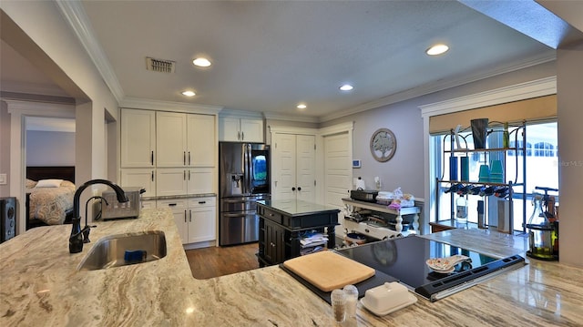 kitchen featuring sink, stainless steel fridge with ice dispenser, a kitchen island, light stone countertops, and white cabinets