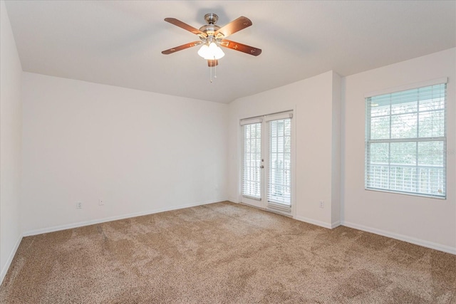 carpeted spare room featuring ceiling fan and french doors