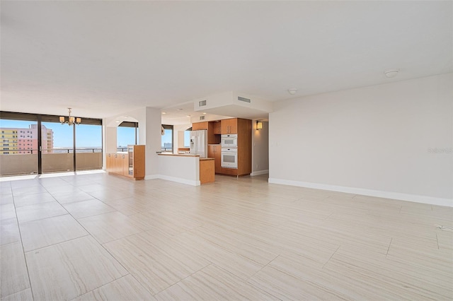 unfurnished living room with expansive windows and an inviting chandelier