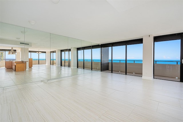 unfurnished room featuring a chandelier, a wealth of natural light, and a water view