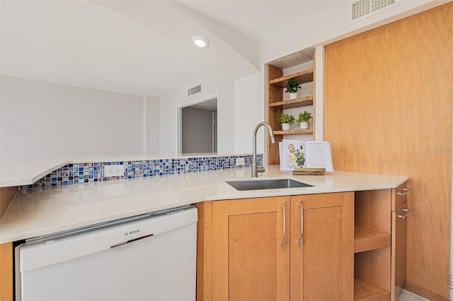 kitchen with white dishwasher, sink, decorative backsplash, and kitchen peninsula