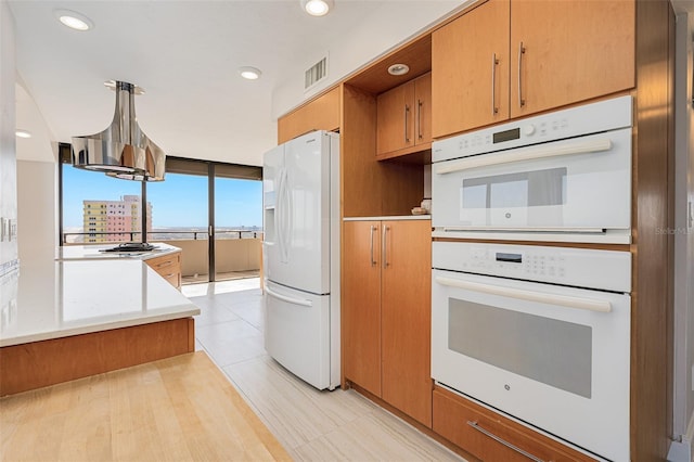 kitchen with a notable chandelier, white appliances, range hood, and pendant lighting