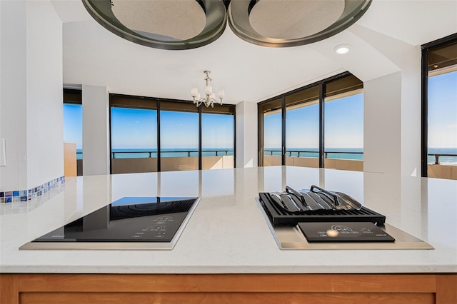 kitchen featuring a chandelier, black electric cooktop, a water view, and a healthy amount of sunlight