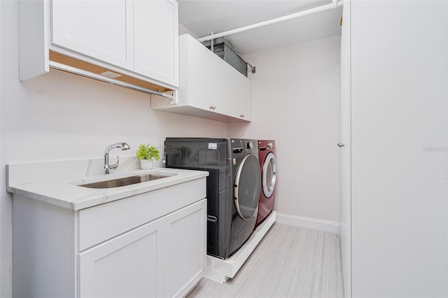 washroom with cabinets, sink, a textured ceiling, and independent washer and dryer