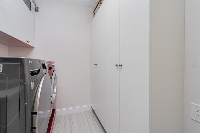 laundry area featuring washer and dryer, a textured ceiling, and cabinets