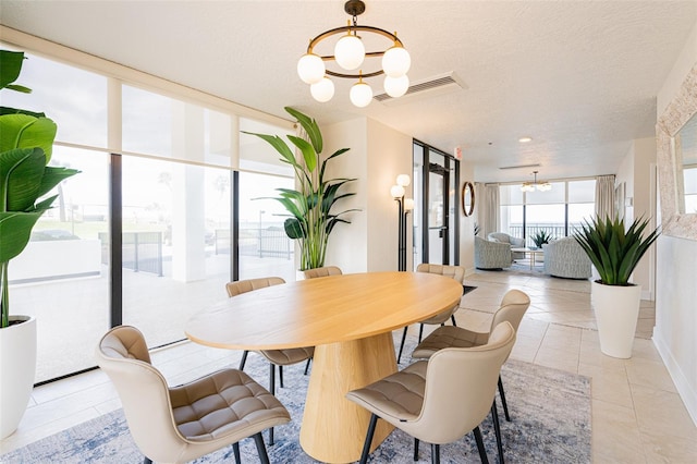 dining space with a textured ceiling, light tile patterned floors, expansive windows, and a notable chandelier