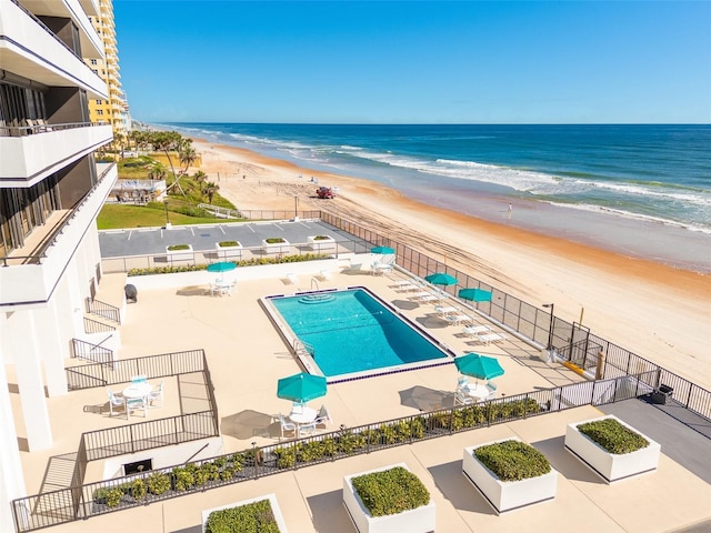 view of pool with a water view, a patio, and a beach view