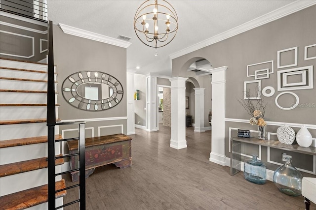 interior space featuring decorative columns, hardwood / wood-style floors, crown molding, and a chandelier