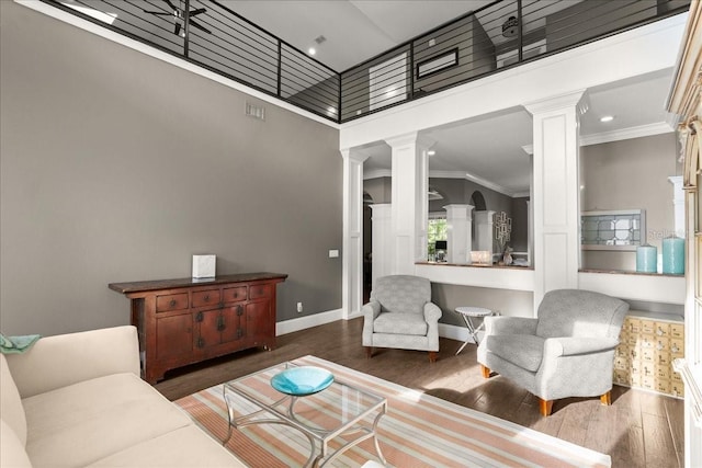 living room with ornamental molding, dark hardwood / wood-style flooring, a high ceiling, and decorative columns