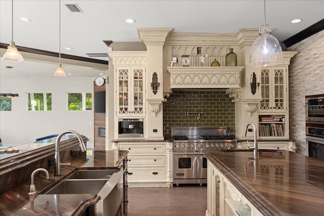 kitchen with stainless steel appliances, cream cabinetry, hanging light fixtures, and sink