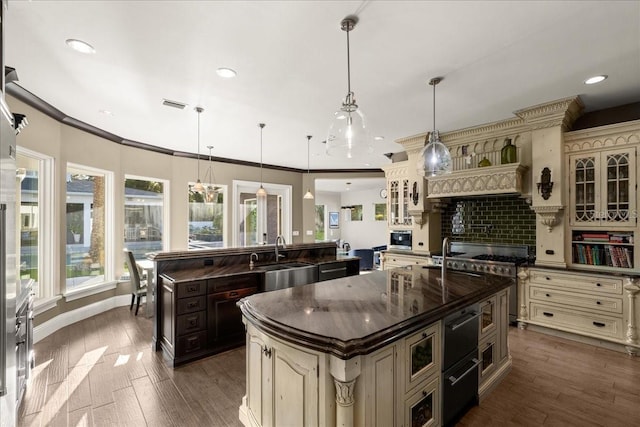 kitchen featuring hanging light fixtures, cream cabinets, sink, and a center island with sink