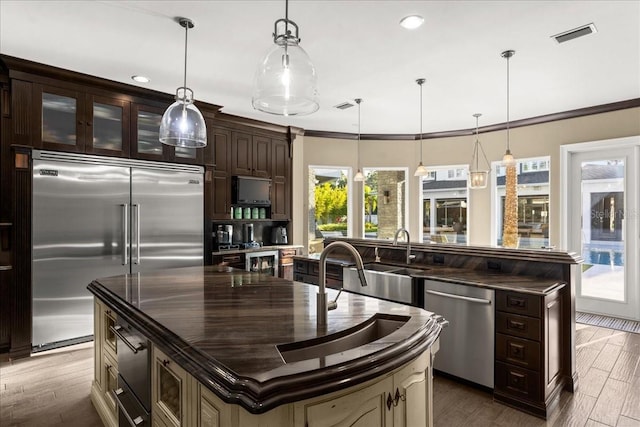 kitchen featuring dark brown cabinets, a kitchen island, stainless steel appliances, and pendant lighting