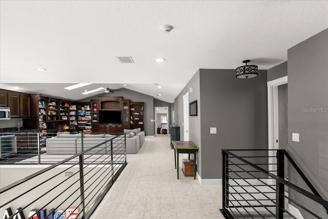 hall featuring lofted ceiling and a textured ceiling