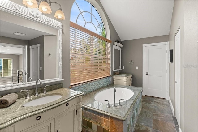 bathroom featuring tiled tub, vanity, a wealth of natural light, and vaulted ceiling