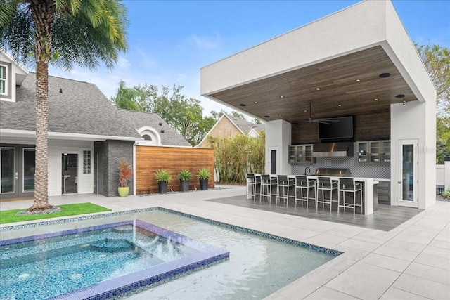 view of swimming pool featuring ceiling fan, exterior bar, a hot tub, grilling area, and a patio