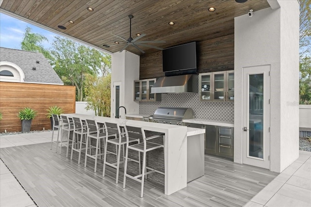 view of patio / terrace with ceiling fan, an outdoor wet bar, a grill, and exterior kitchen