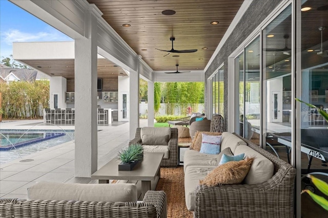 view of patio with a bar, a fenced in pool, ceiling fan, an outdoor living space, and pool water feature