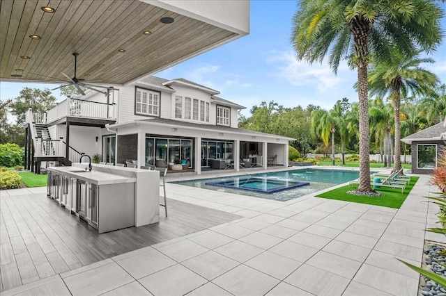 back of property featuring a patio area, ceiling fan, a pool with hot tub, and a wet bar