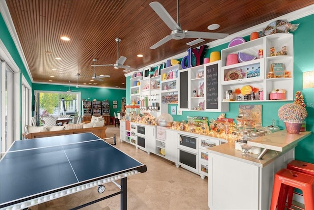 recreation room with ceiling fan, crown molding, and wooden ceiling