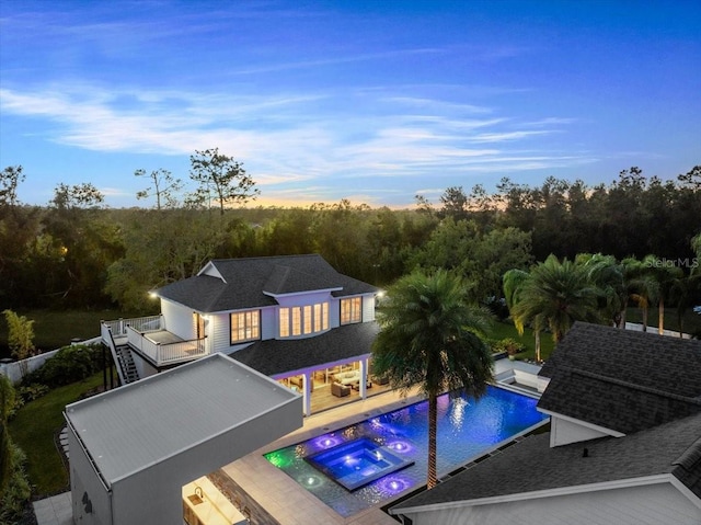 exterior space featuring a swimming pool with hot tub, a patio area, and a balcony