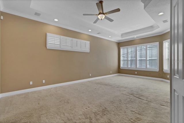 unfurnished room featuring light carpet, ceiling fan, a raised ceiling, a textured ceiling, and crown molding