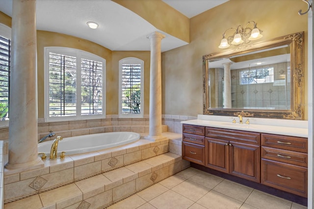 bathroom with vanity, tile patterned flooring, a relaxing tiled tub, and decorative columns