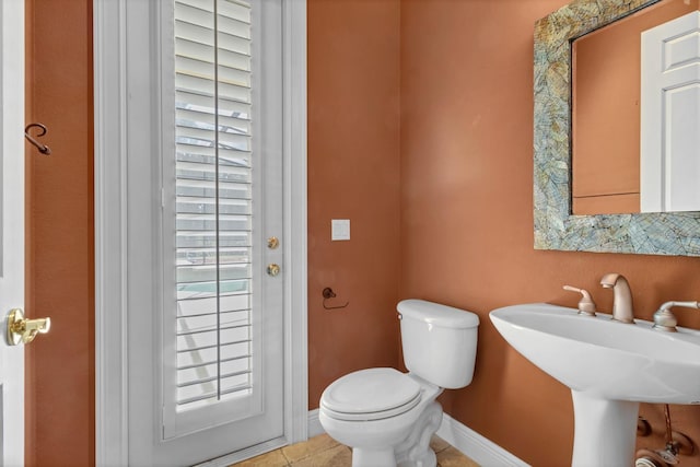 bathroom with toilet, tile patterned floors, and sink