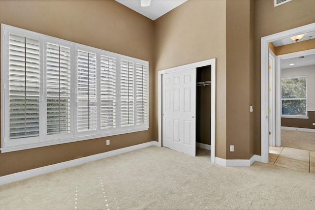 unfurnished bedroom with light colored carpet and a closet