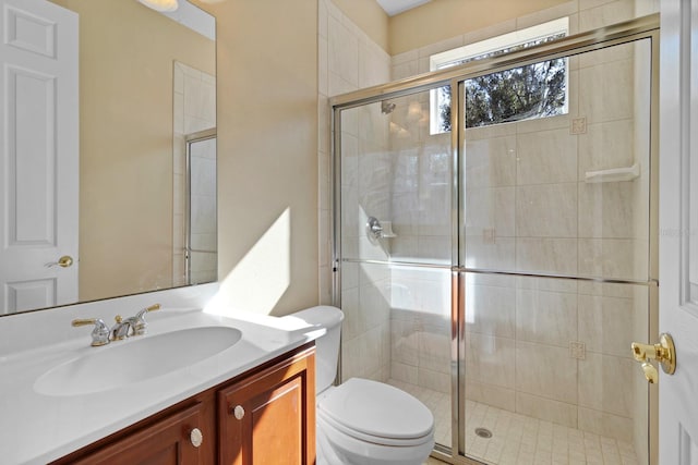 bathroom featuring toilet, vanity, and a shower with door