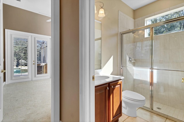 bathroom with a shower with shower door, vanity, tile patterned floors, and toilet