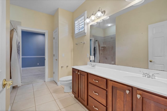 bathroom with toilet, vanity, a tile shower, and tile patterned flooring