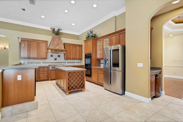 kitchen with custom exhaust hood, appliances with stainless steel finishes, crown molding, and a center island