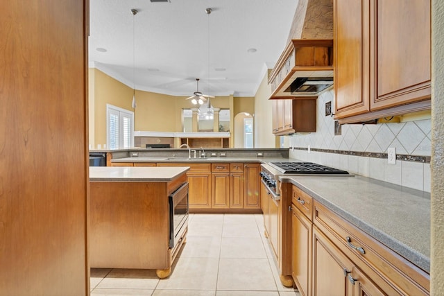 kitchen featuring a center island, sink, backsplash, ceiling fan, and light tile patterned floors