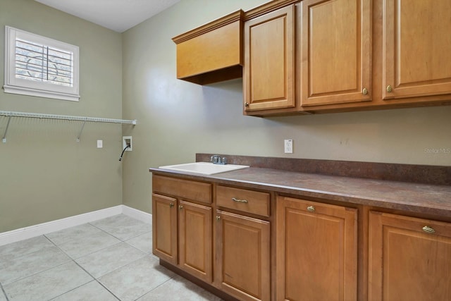 washroom featuring washer hookup, light tile patterned flooring, sink, and cabinets