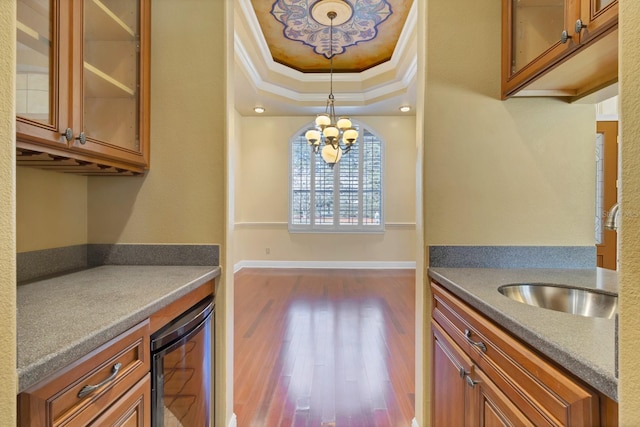 kitchen with wine cooler, pendant lighting, sink, a tray ceiling, and ornamental molding