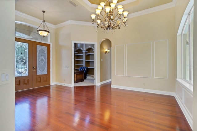 foyer featuring hardwood / wood-style floors, a chandelier, crown molding, and french doors