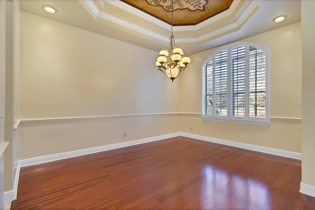 spare room featuring ornamental molding, dark hardwood / wood-style flooring, a raised ceiling, and a chandelier