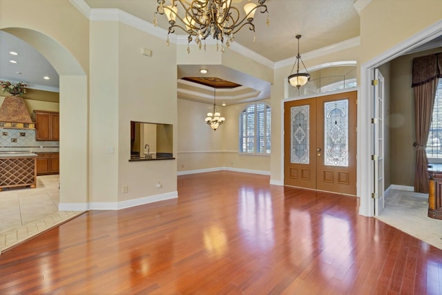 entryway featuring light hardwood / wood-style floors, a notable chandelier, french doors, crown molding, and sink