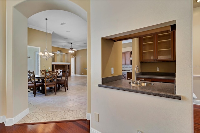 kitchen featuring decorative light fixtures, wood-type flooring, crown molding, ceiling fan with notable chandelier, and sink